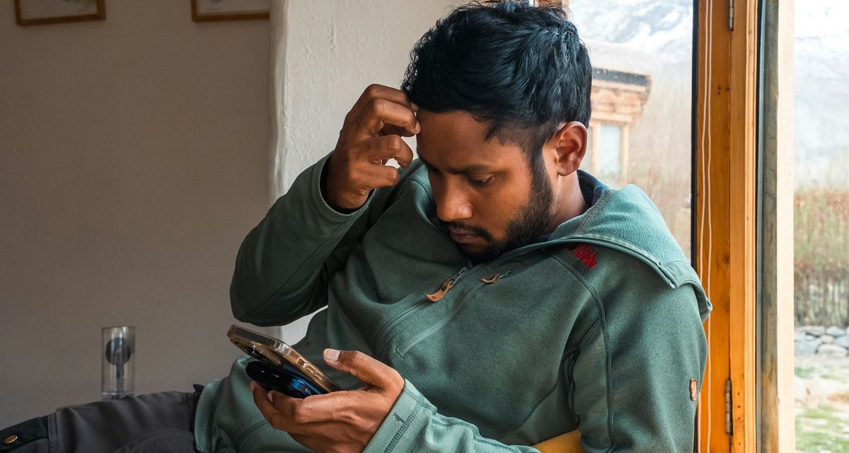 Un artisan lit un message sur son téléphone, l'air préoccupé